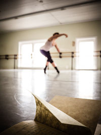 Close-up of book with woman performing ballet dance in background at studio