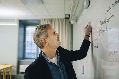 Male teacher erasing text on whiteboard