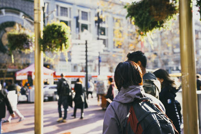 Rear view of people walking on road in city