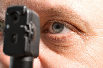 Close-up of woman looking through otoscope