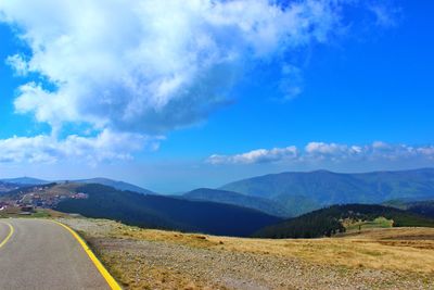 Scenic view of landscape and mountains against blue sky