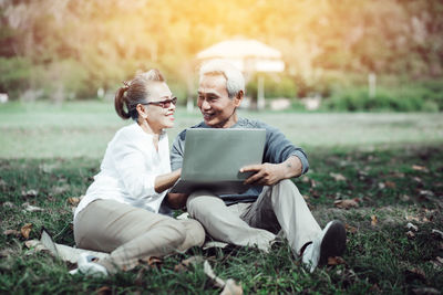 Young man using phone while sitting on grass