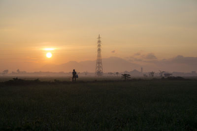 Silhouette people on field against sky during sunset