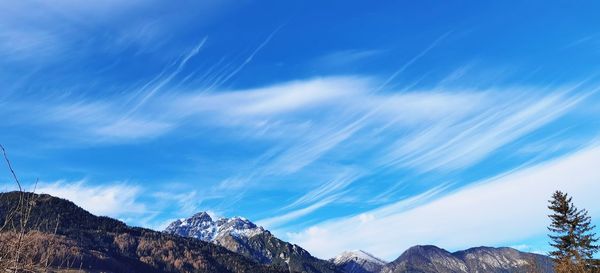 Low angle view of snowcapped mountains against blue sky