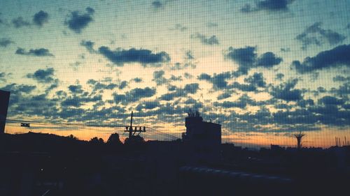 Silhouette of city against sky during sunset