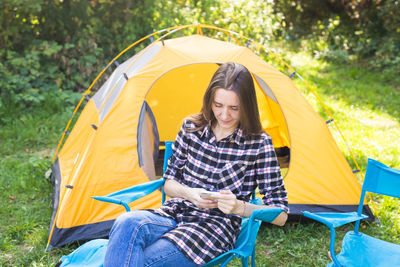 Beautiful young woman sitting on tent