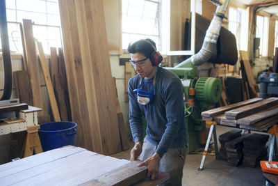 Male carpenter holding wooden plank at workshop