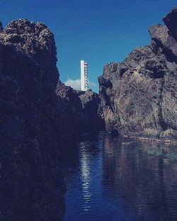 Scenic view of cliff by sea against clear sky