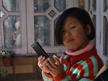 Portrait of cute girl holding mobile phone