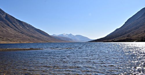 Scenic view of lake and mountains against clear blue sky
