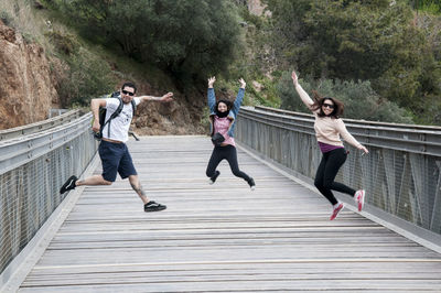 People jumping on footbridge