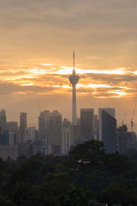 Modern buildings in city against sky during sunset