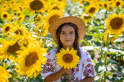 Portrait of young woman standing against yellow flower