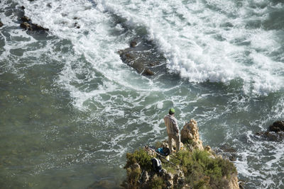 High angle view of man on rock in sea