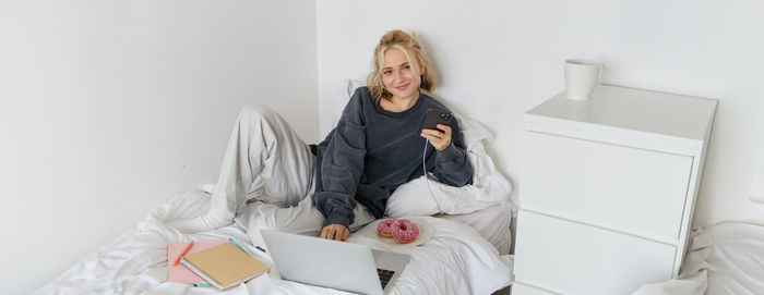 Portrait of young woman sitting on sofa at home