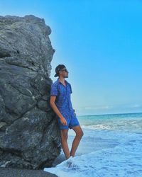 Full length of man standing on rock at shore against clear sky