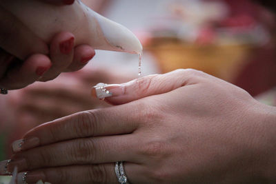 Cropped image of woman pouring water on female friends hands