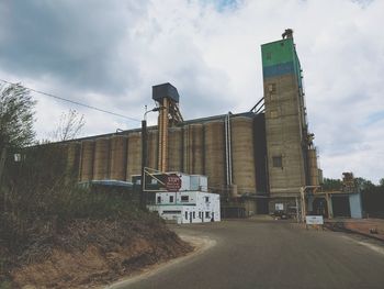 Road by factory against sky