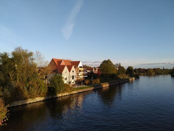 Houses by lake and buildings against sky