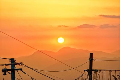 Silhouette electricity pylon against romantic sky at sunset