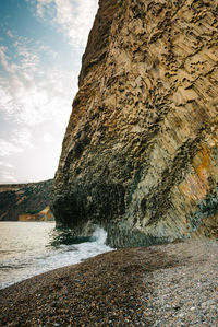 Rock formation on beach against sky