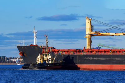 Cranes at commercial dock against sky