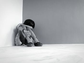 Girl sitting on floor by wall