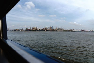 City at waterfront against cloudy sky