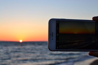 Close-up of sea against clear sky during sunset