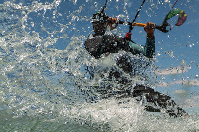 High angle view of man kitesurfing in sea against sky