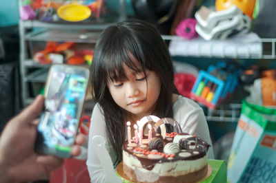 Close-up of cute girl sitting by cake at home