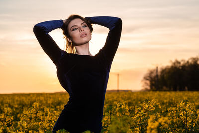 Happy woman standing on field against sky during sunset