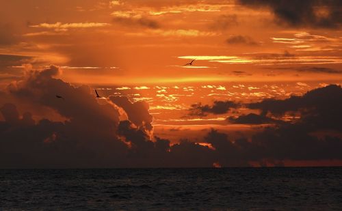 Scenic view of sea against dramatic sky during sunset