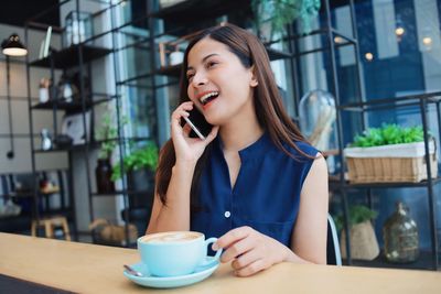 Young woman using mobile phone in cafe