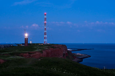 Lighthouse by sea against blue sky