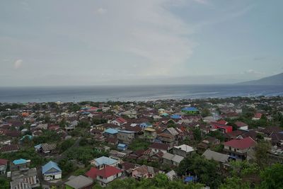 High angle view of townscape by sea against sky