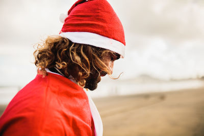 Side view of man wearing santa costume at beach