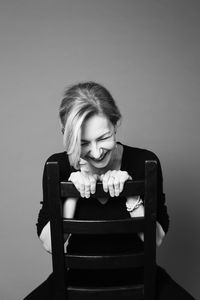 Smiling mature woman sitting against wall