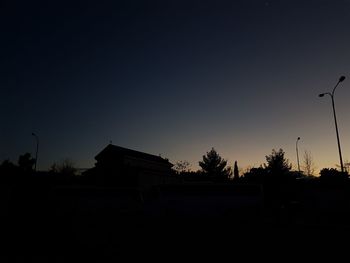 Silhouette houses and trees against sky at sunset