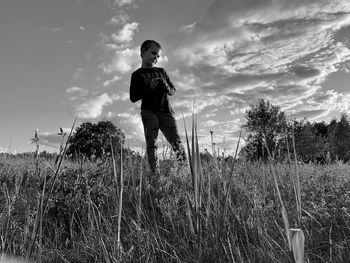 Low angle view of boy standing on grassy land