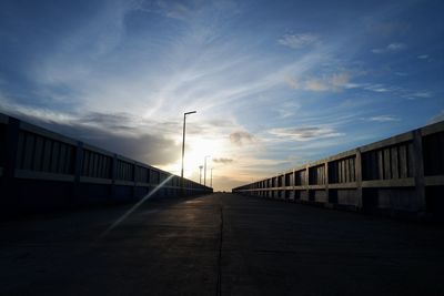 Empty road along buildings at sunset
