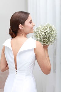 Side view of  woman with uptied hairstyle in wedding dress holding bouquet