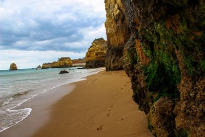 Rock formations on beach against sky