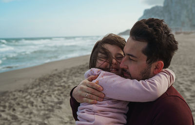 Rear view of father and daughter on beach