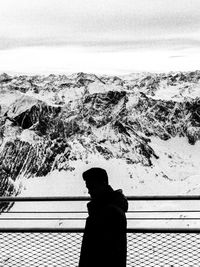 Side view of man standing by railing against sea