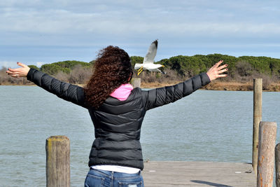 Woman with arms outstretched on pier