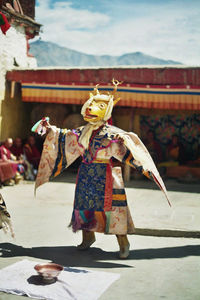 Performer in costume dancing outside temple during festival