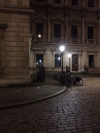 Illuminated street by building at night