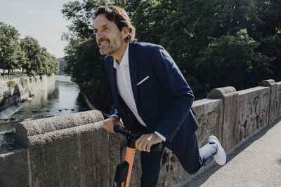 Businessman with e-scooter on a bridge