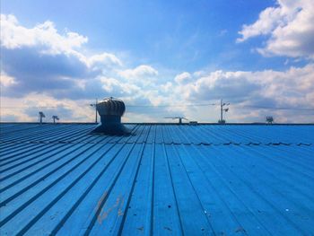 Low angle view of ventilator on blue industry roof against sky